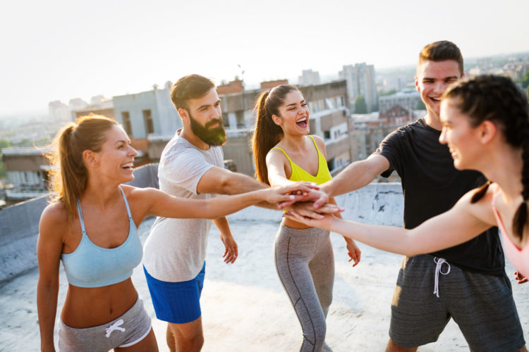 Group of happy fit friends exercising outdoor in city Group of fit happy people training outdoor on the roof