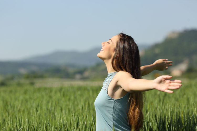 Happy woman breathing deeply fresh air in a field Side view portrait of a happy woman breathing deeply fresh air in a green field